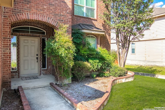 view of exterior entry featuring a lawn