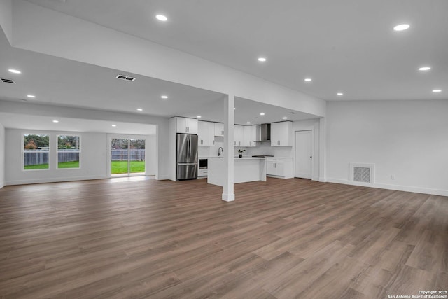 unfurnished living room featuring sink and hardwood / wood-style flooring