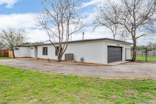 rear view of property featuring cooling unit, a yard, and a garage