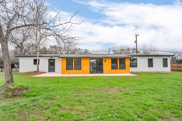 rear view of house featuring a lawn and a patio