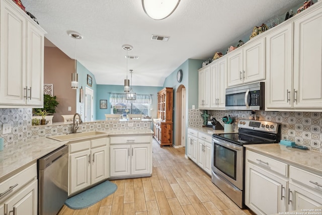 kitchen with sink, stainless steel appliances, hanging light fixtures, and white cabinets