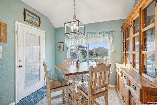 dining room with vaulted ceiling, a chandelier, and light hardwood / wood-style flooring