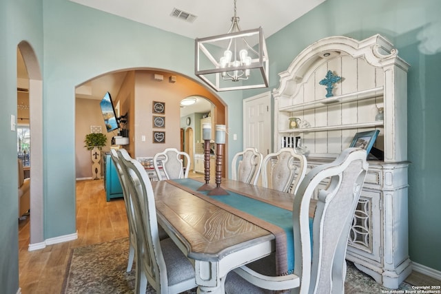 dining area with wood-type flooring and an inviting chandelier