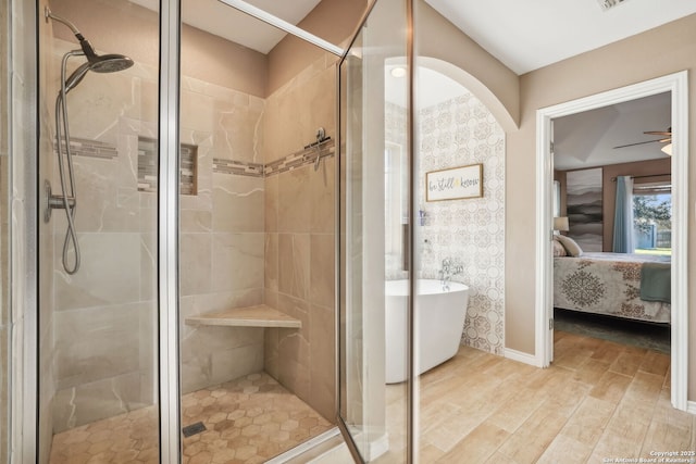 bathroom featuring plus walk in shower, hardwood / wood-style floors, and ceiling fan