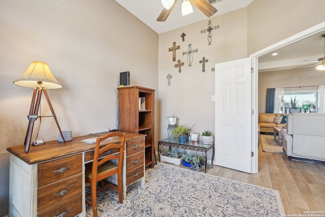 home office with ceiling fan, vaulted ceiling, and light hardwood / wood-style flooring