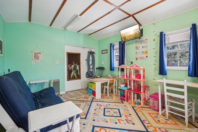 recreation room featuring vaulted ceiling, radiator heating unit, and hardwood / wood-style floors