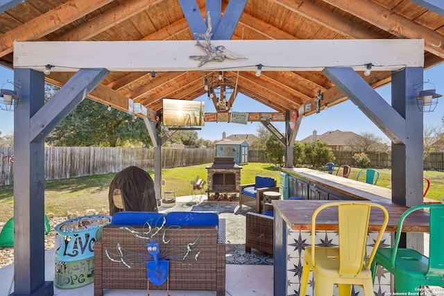 view of patio / terrace featuring a bar, a gazebo, and an outdoor stone fireplace