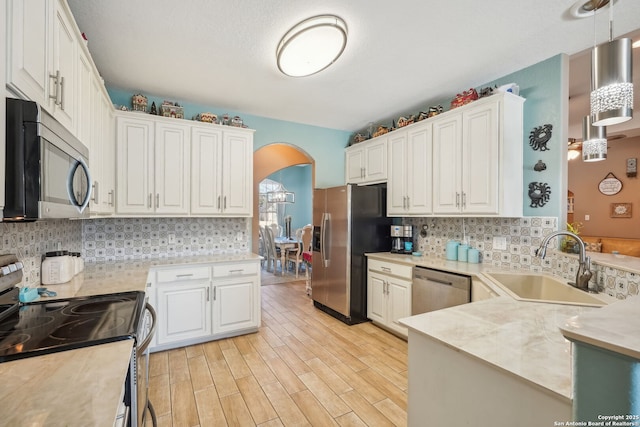 kitchen with pendant lighting, sink, stainless steel appliances, and white cabinets