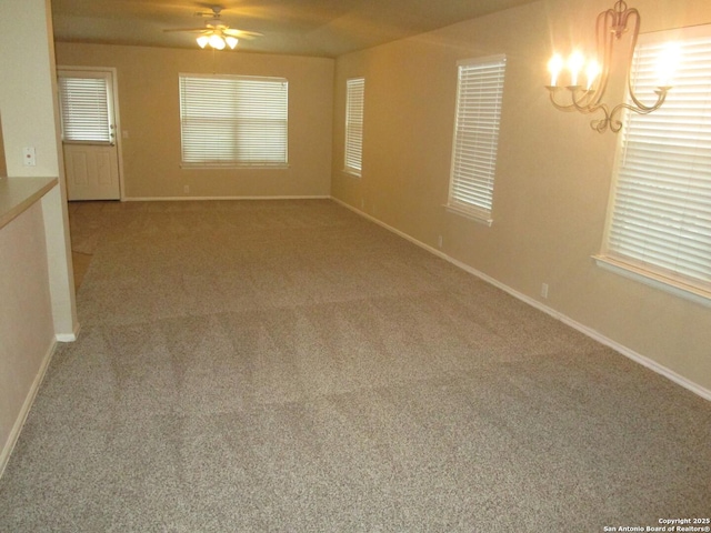 unfurnished room with plenty of natural light, ceiling fan with notable chandelier, and carpet