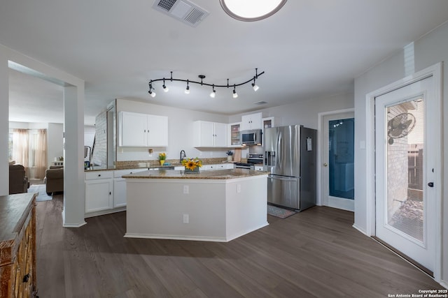 kitchen featuring white cabinetry, appliances with stainless steel finishes, light stone countertops, and dark wood-type flooring