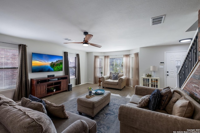 living room with a textured ceiling, wood-type flooring, and ceiling fan