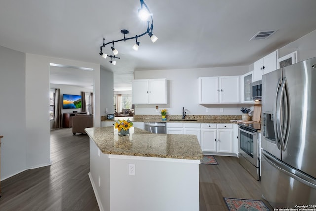 kitchen featuring sink, white cabinetry, stainless steel appliances, light stone countertops, and a kitchen island