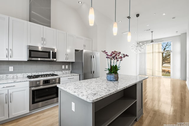 kitchen with a center island, open shelves, stainless steel appliances, decorative backsplash, and light wood-style floors