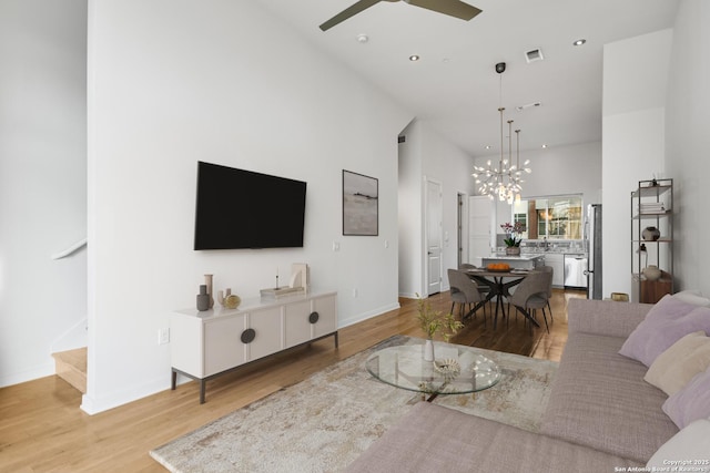 living area with recessed lighting, visible vents, stairway, wood finished floors, and ceiling fan with notable chandelier