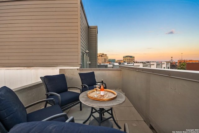 balcony at dusk featuring a view of city