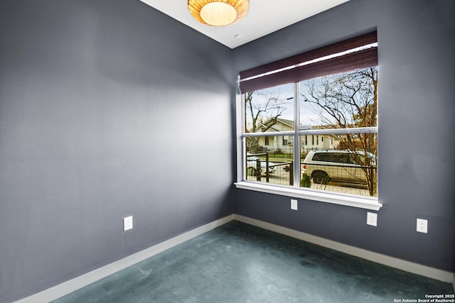 spare room with concrete floors and baseboards