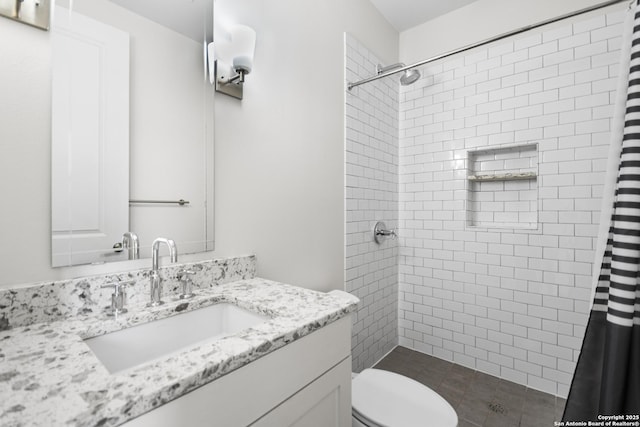 full bath with toilet, tiled shower, and vanity