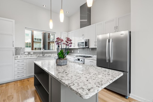 kitchen with tasteful backsplash, a towering ceiling, stainless steel appliances, white cabinetry, and a sink