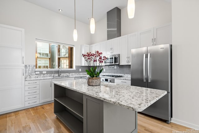 kitchen featuring white cabinets, a towering ceiling, appliances with stainless steel finishes, open shelves, and a sink