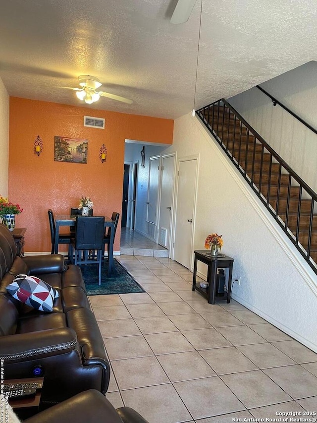 tiled living room featuring ceiling fan and a textured ceiling