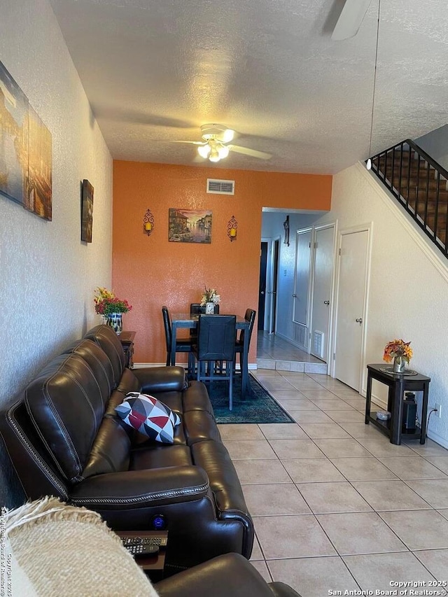 tiled living room with a textured ceiling and ceiling fan