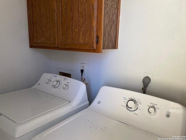 clothes washing area featuring washer and dryer and cabinets