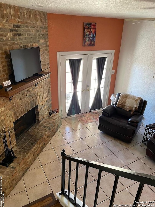 living room with tile patterned flooring, a brick fireplace, french doors, and a textured ceiling