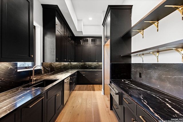 kitchen with sink, stainless steel dishwasher, dark stone counters, light hardwood / wood-style floors, and decorative backsplash