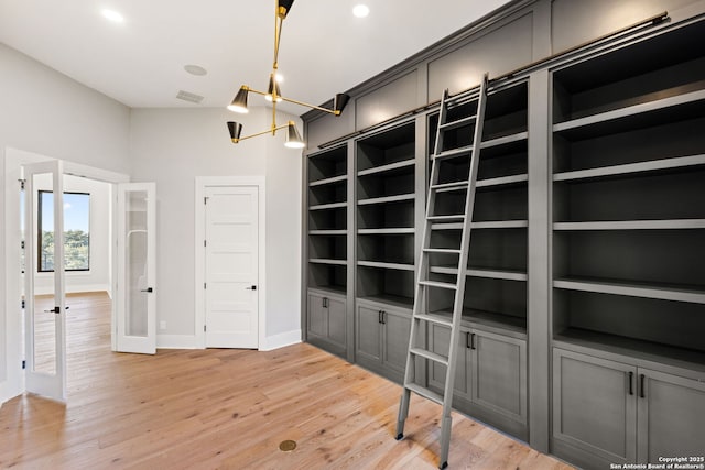 interior space featuring french doors, built in features, an inviting chandelier, and light hardwood / wood-style flooring