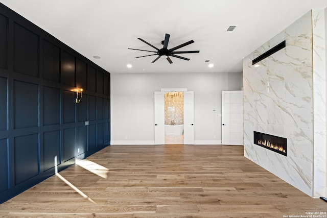 unfurnished living room featuring light hardwood / wood-style flooring, a high end fireplace, and ceiling fan