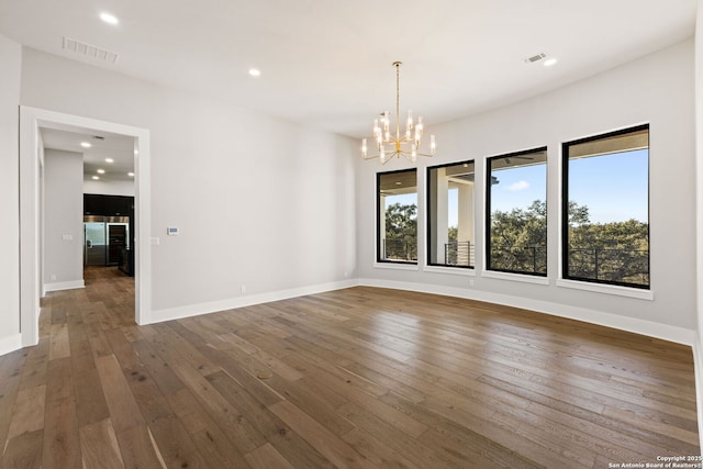 unfurnished dining area with dark wood-type flooring, a healthy amount of sunlight, and a chandelier