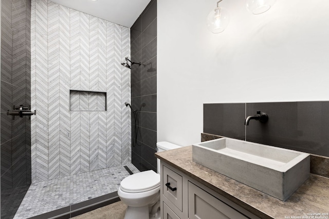 bathroom featuring vanity, a tile shower, and toilet