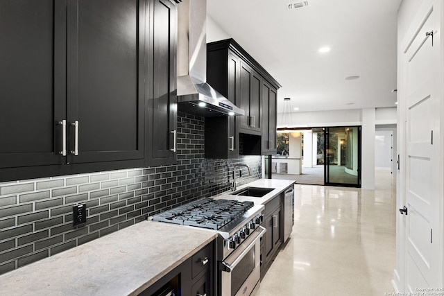 kitchen with decorative light fixtures, tasteful backsplash, sink, stainless steel appliances, and wall chimney range hood