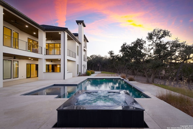 pool at dusk with an in ground hot tub, ceiling fan, and a patio