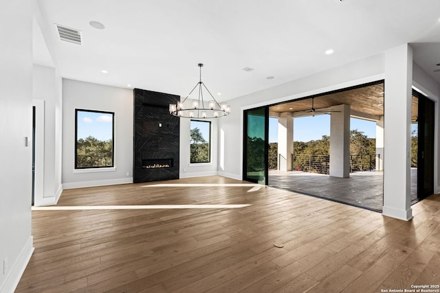 unfurnished living room with hardwood / wood-style floors, a fireplace, and a chandelier