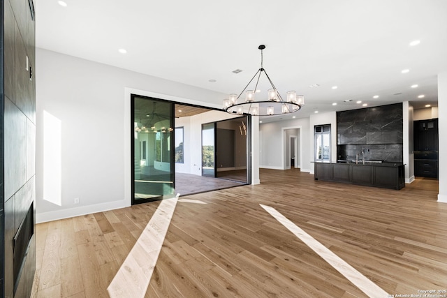 unfurnished dining area featuring a barn door, a chandelier, and light wood-type flooring