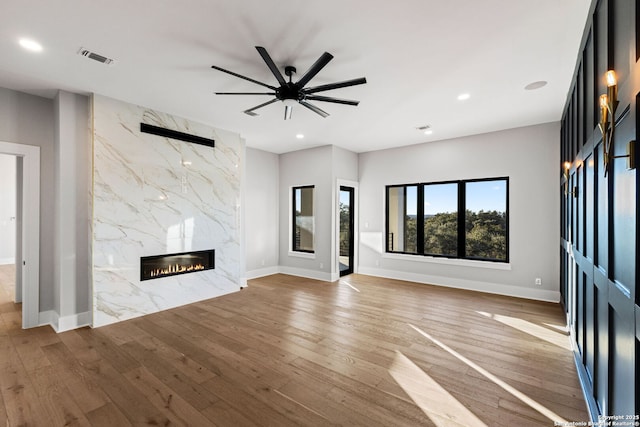 unfurnished living room with ceiling fan, a fireplace, and wood-type flooring