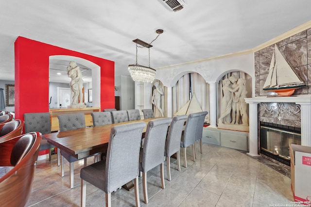 dining area with an inviting chandelier, ornamental molding, a tile fireplace, and light tile patterned floors