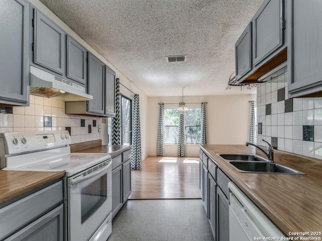 kitchen featuring gray cabinets, butcher block counters, sink, and white appliances