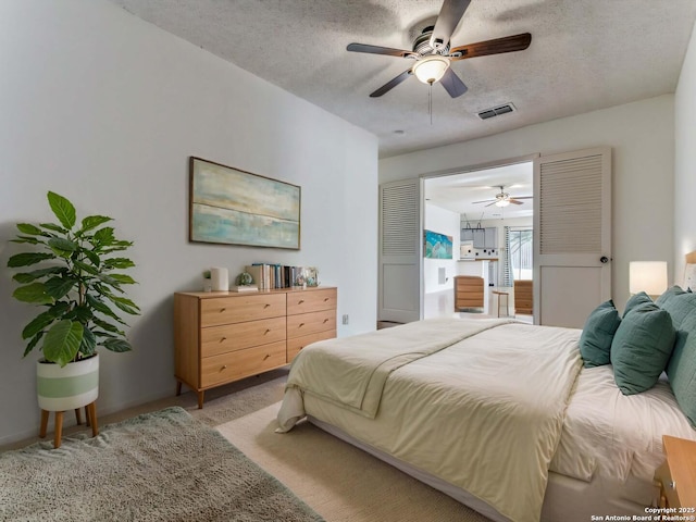 carpeted bedroom featuring ceiling fan and a textured ceiling