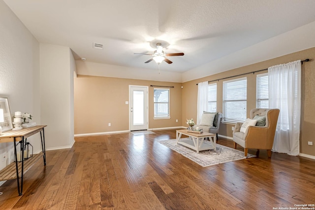 living area with hardwood / wood-style flooring, a textured ceiling, and ceiling fan