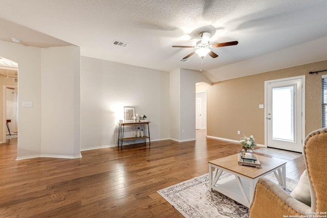 living room with dark hardwood / wood-style flooring, a textured ceiling, and ceiling fan