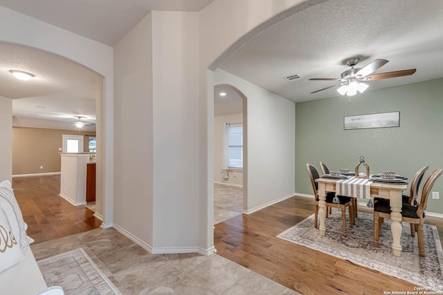 dining space with a textured ceiling, ceiling fan, and light wood-type flooring