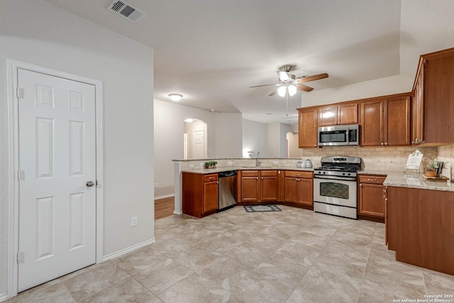 kitchen with sink, kitchen peninsula, ceiling fan, stainless steel appliances, and decorative backsplash