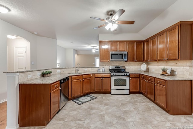 kitchen featuring sink, tasteful backsplash, kitchen peninsula, stainless steel appliances, and light stone countertops