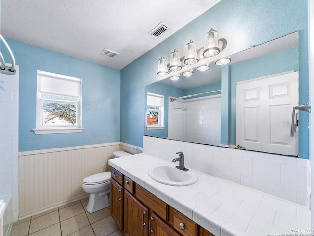 full bathroom featuring tiled shower / bath, vanity, toilet, tile patterned floors, and a textured ceiling