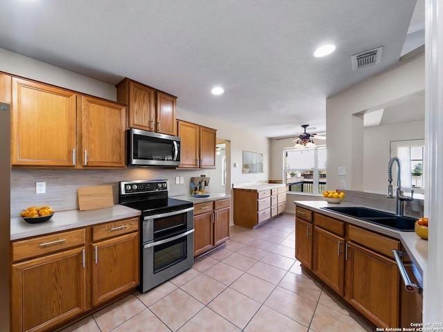 kitchen featuring light tile patterned flooring, sink, appliances with stainless steel finishes, ceiling fan, and backsplash