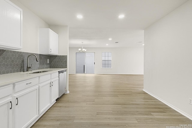 kitchen with sink, white cabinetry, tasteful backsplash, light wood-type flooring, and dishwasher