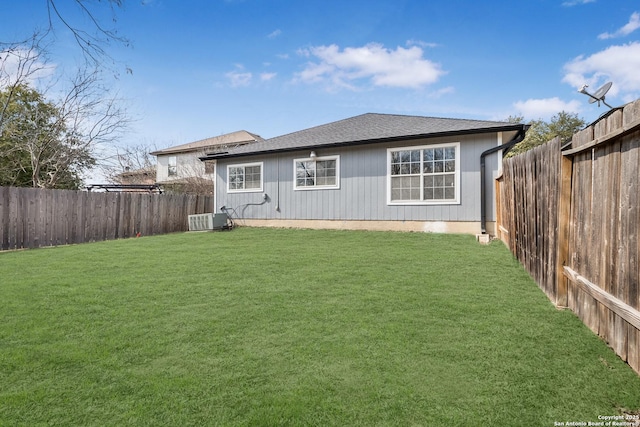 rear view of house featuring central air condition unit and a lawn