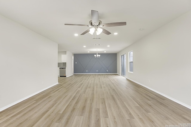 unfurnished living room with ceiling fan with notable chandelier and light hardwood / wood-style flooring